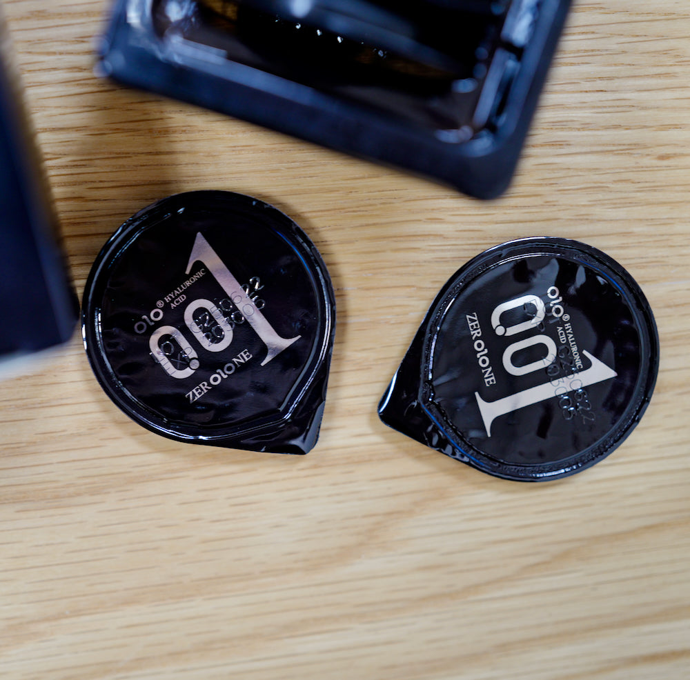 Two black OLO condom wrappers on a wooden table