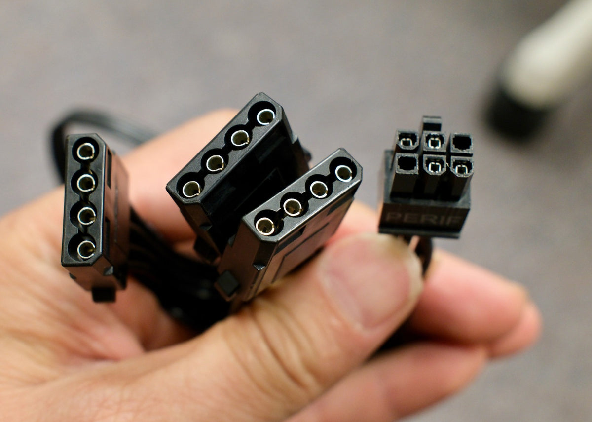 Hand holding the Molex connectors and 6-pin plug of the EVGA cable