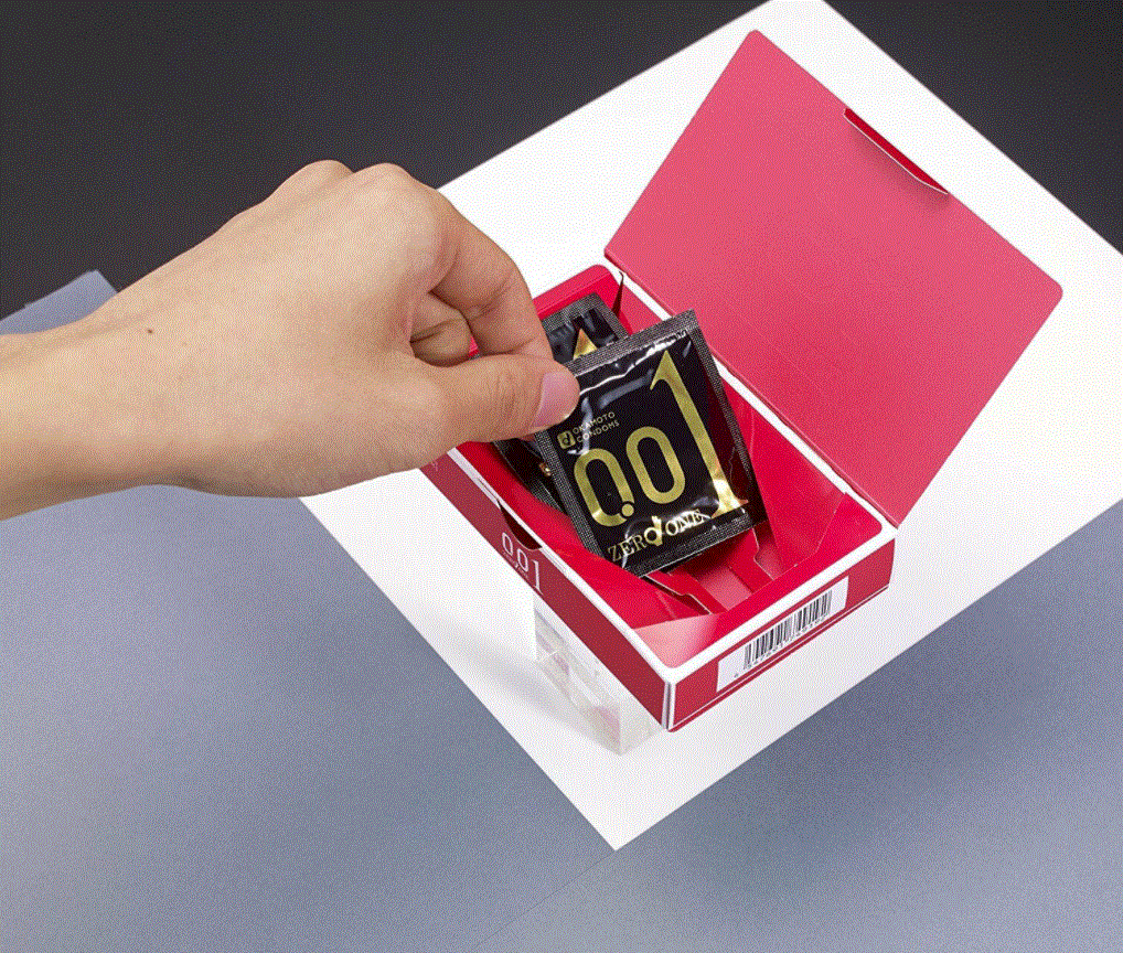 Hand taking a condom wrapper out of an open Okamoto 001 retail box